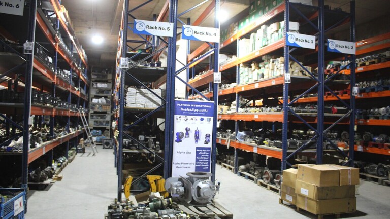 Organized warehouse with branded rack signs at Platinum International