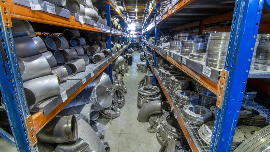 Wide warehouse aisle showing thousands of industrial flanges and fittings
